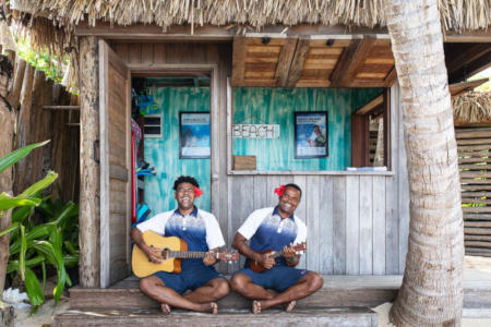 Two Kokomo staff members playing the guitar in front of the beach shack.
