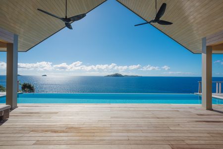 A view looking out across the deck and infinity pool of one of the luxury Kokomo hilltop residences, with neighbouring islands visible across the calm, wide ocean.