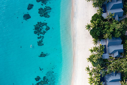 A guest walking along the beach at Kokomo Private Island Fiji.