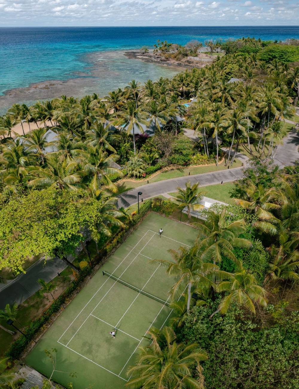 A birds eye view of two guests enjoying a game of tennis at Kokomo Island Fiji.