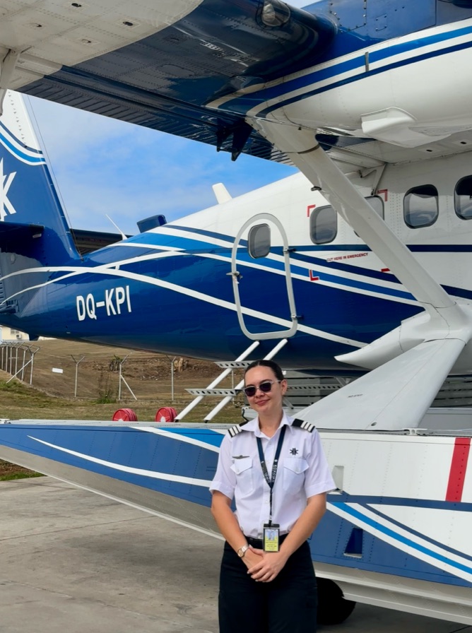Cynthia standing next to the sea plane while parked on land.