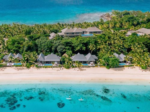 An aerial view showing the whole of Kokomo Private Island Fiji and some neighbouring islands in the distance.