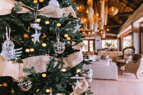 A richly-decorated Christmas tree with ocean-themed baubles and other adornments in the entrance lounge area of Kokomo Island Fiji, with the lounge area out of focus in the background.