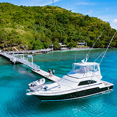 A large fishing vessel docked at a jetty at Kokomo Private Island Fiji, with the island greenery visible in the distance.