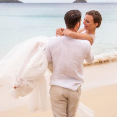 A man carrying a woman down to the water at one of the beaches at Kokomo Private Island Fiji.