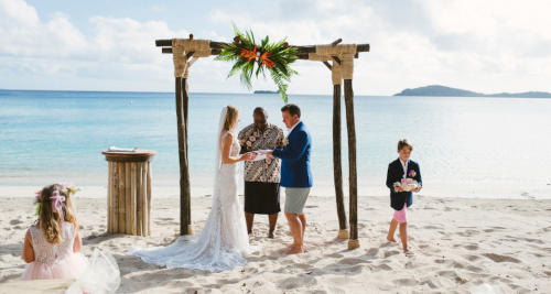 A bride and groom walking towards the beach at Kokomo Private Island Fiji