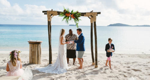 A bride and groom walking towards the beach at Kokomo Private Island Fiji.