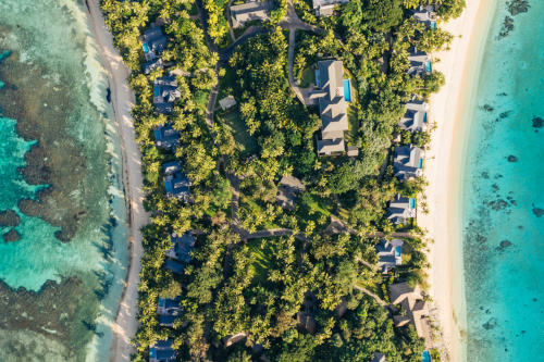 A bird's-eye view of the middle section of the island showing some of the villas, a tennis court, and one of the residences at Kokomo Private Island.
