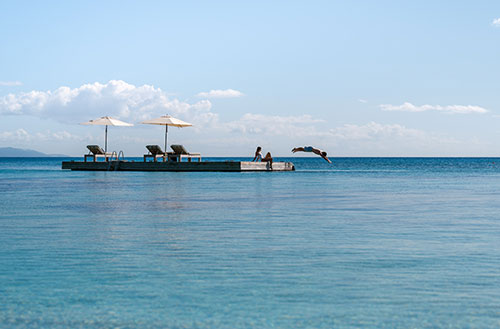 A couple enjoying the floating pontoon at Kokomo Island Fiji.
