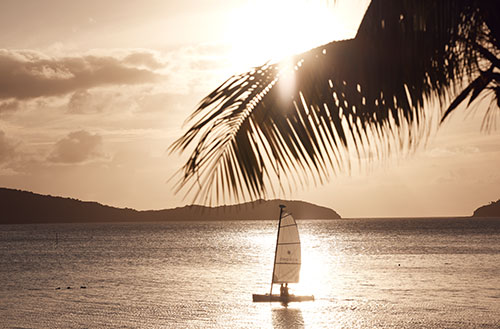 Guests at Kokomo Island Fiji sailing a Hobie Cat at sunset.