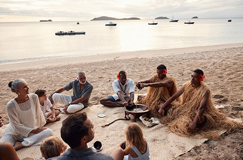 A family sitting on the beach at sunset