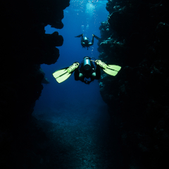 Divers swimming between two large walls covered with coral at Kokomo Island Fiji