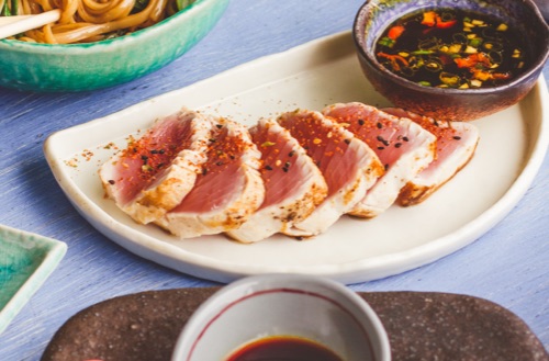 Multiple food dishes including sashimi spread out across a table.