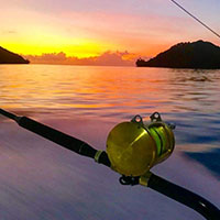 A fishing rod cast out into the water at sunset off the coast of Kokomo Private Island Fiji