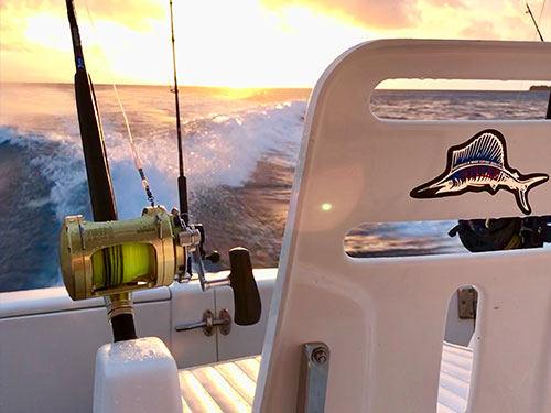 Close up of fishing rod and seat on boat overlooking the sunset