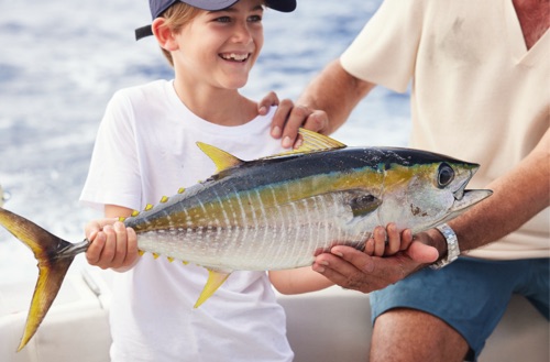 Young boy holding a fish caught locally off the shore of Kokomo Private Island Fiji.