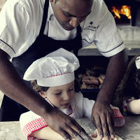 A child learning to make pizza with a Kokomo Private Island chef