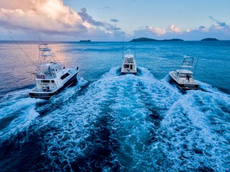 Thee of Kokomo’s large fishing boats cruising out towards the calm open ocean at sunrise, leaving a large wash behind them.