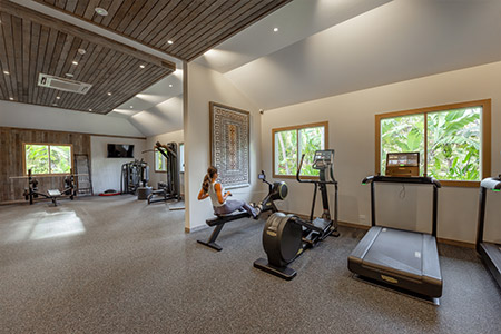 A guest working out inside a tastefully appointed gym at Kokomo Island Fiji.