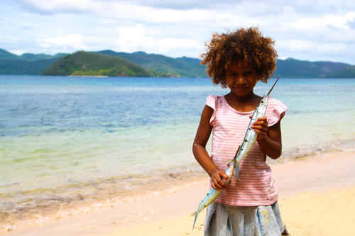 A child holding freshly-caught fish on the beach at Kokomo Private Island Fiji