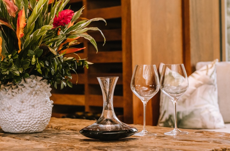 Wine glasses and jug next to flowers in large vase on a table at the wine cellar at Kokomo Private Island Fiji