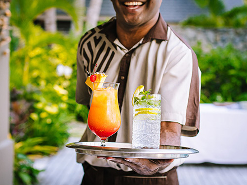 A waiter at Kokocabana presenting a brightly colord cocktail