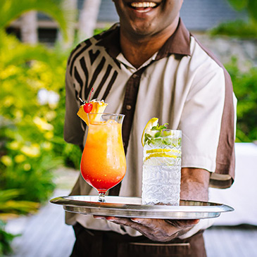 A waiter at Kokocabana presenting a brightly colord cocktail