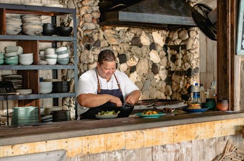 The head chef smiling while preparing a dish at the Walker D’Plank kitchen.
