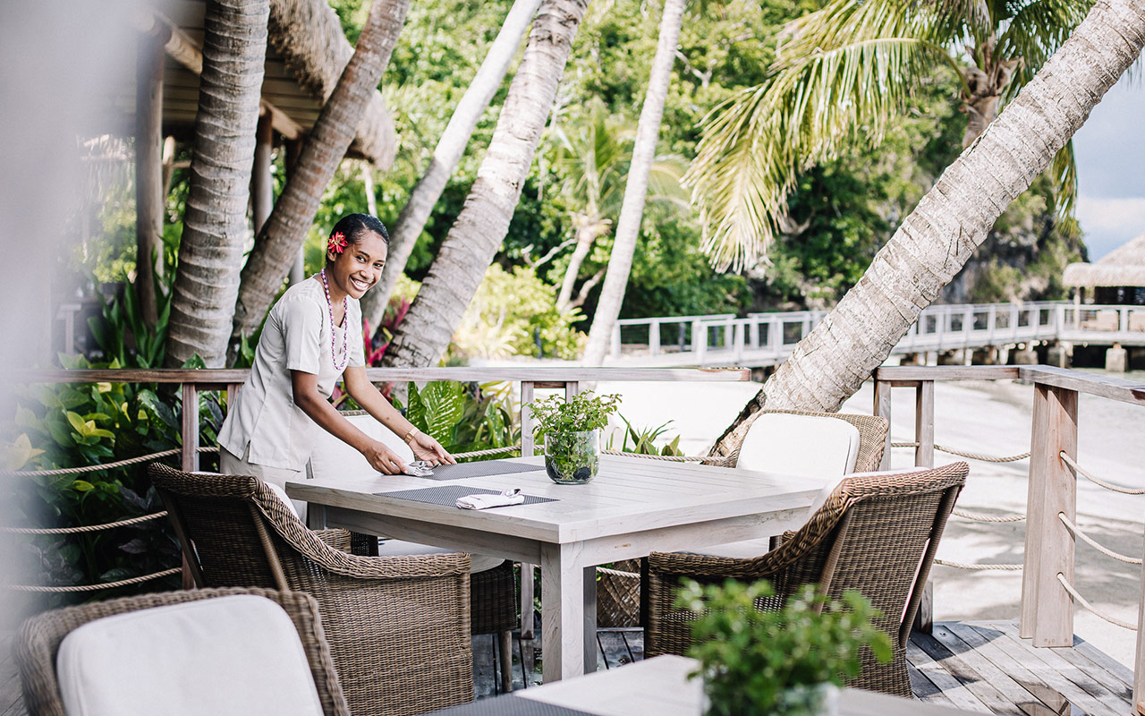 Staff memeber setting an outdoor table up for dining at Kokomo Private Island Fiji