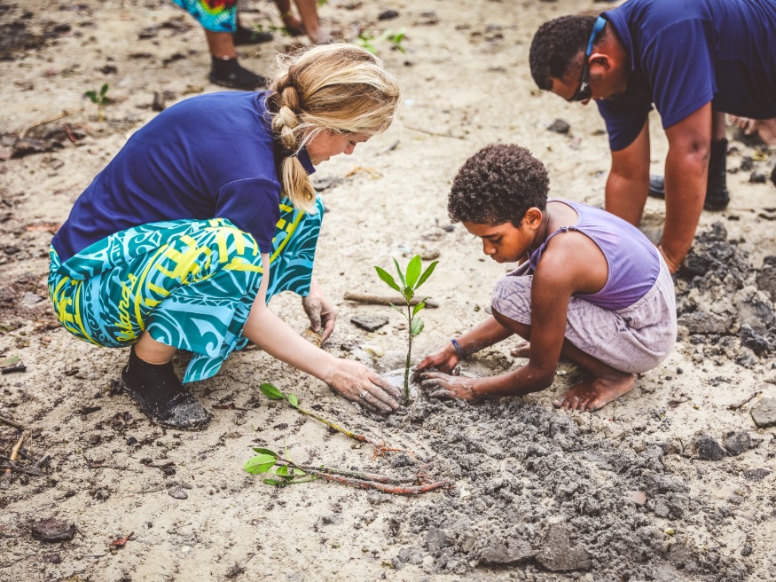 Cliona and child planting a small tree on the island